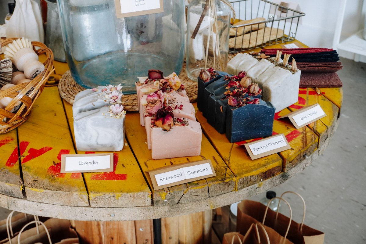 Handmade soaps with dried flowers displayed on a wooden spool table