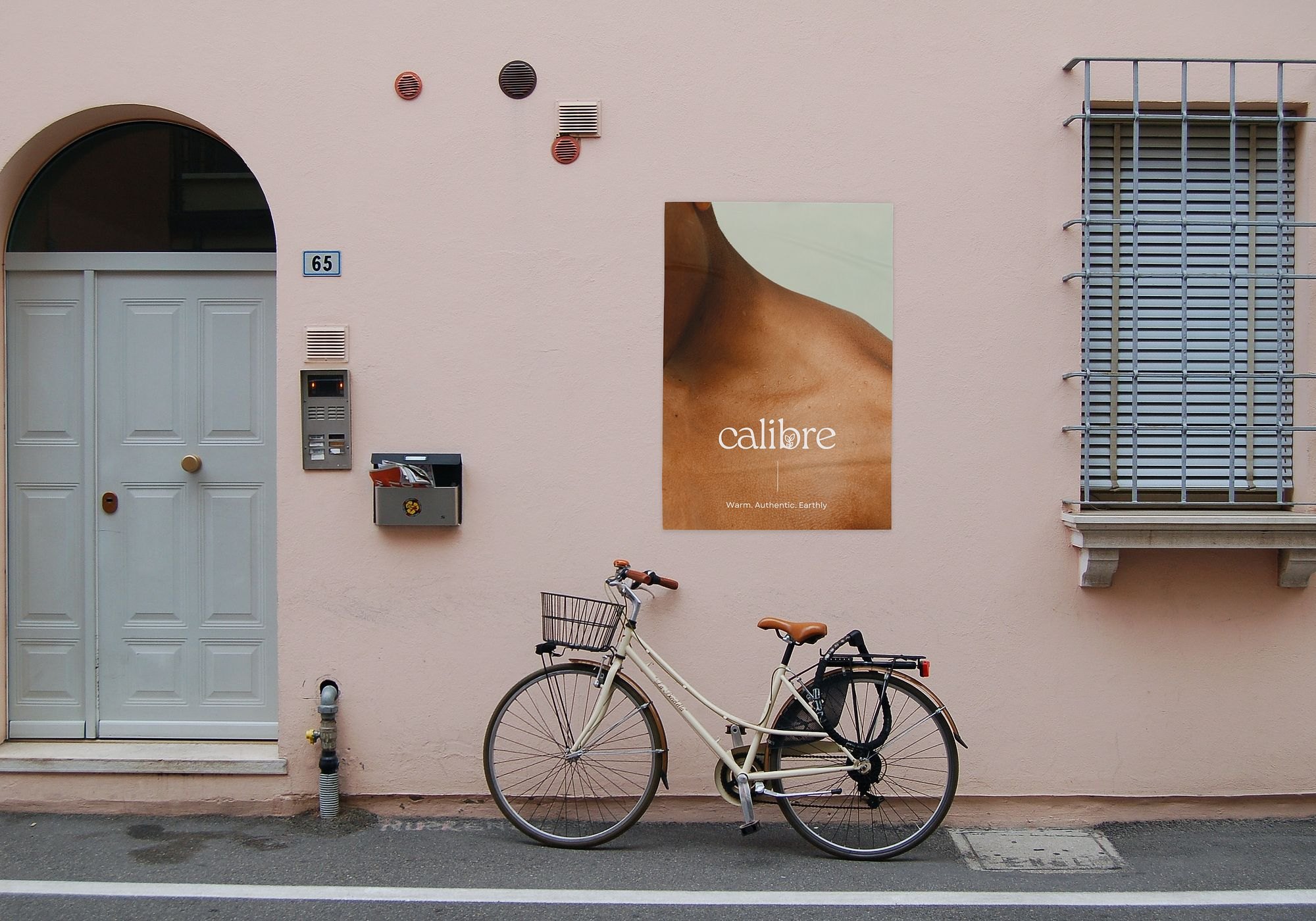 Calibre poster on a pink street wall beside a parked bicycle