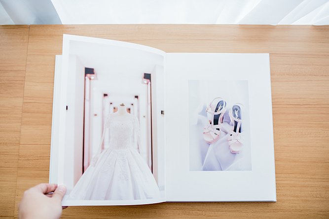 Hand turning the page of a photobook showing a bride in her gown