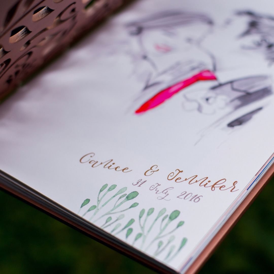 Close-up of an illustrated album page with the couple’s names and date in calligraphy