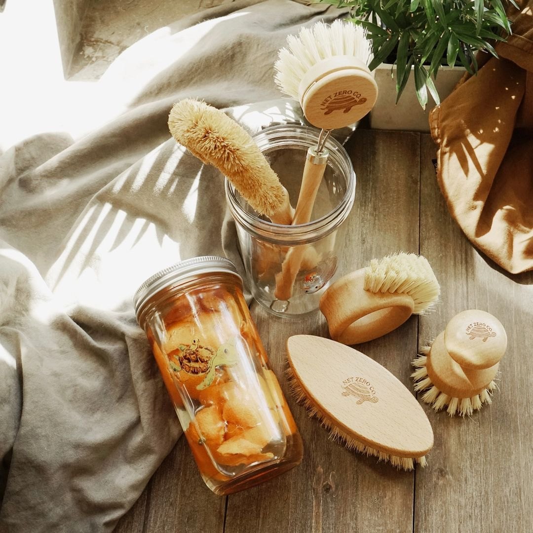 Wooden dish brushes and a jar of pickled vegetables on linen